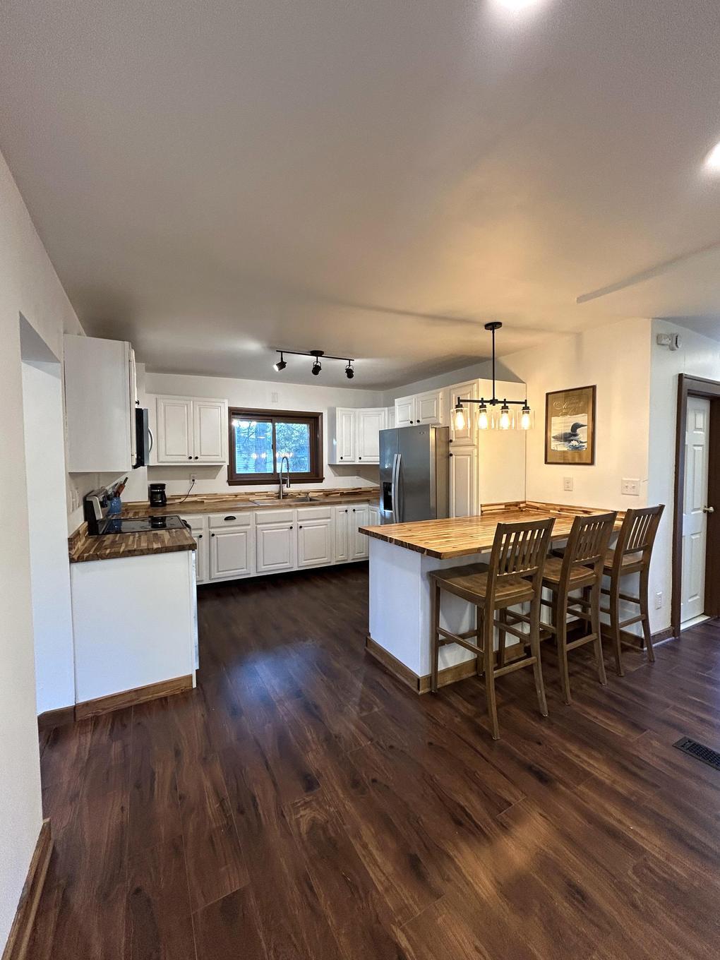 Kitchen with white cabinets, butcher block counters, and dining nook