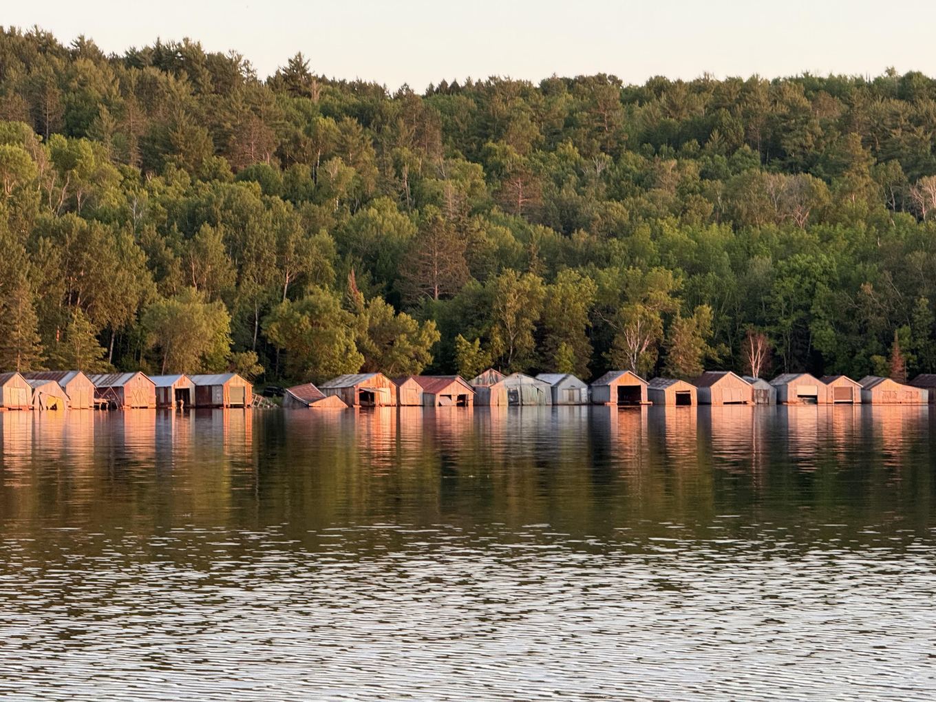 Row of historic wooden boathouses on Lake Vermilion at sunset near the Stuntz Bay launch