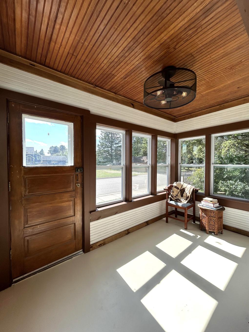 Three-season porch with wood ceiling and wraparound windows
