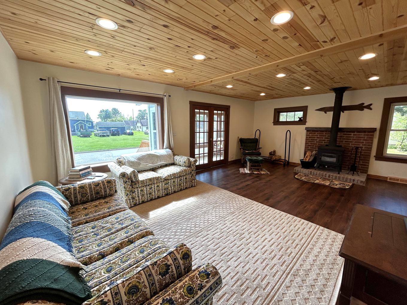 Living room with wood stove, picture window, and knotty pine ceiling