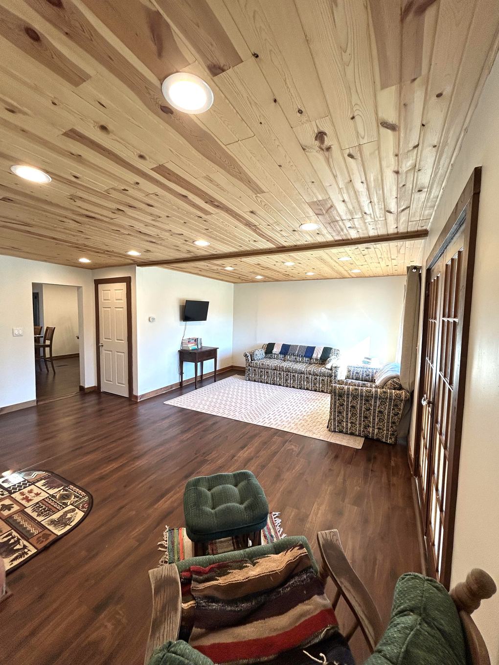 Living room view from the entry with wood stove and wood ceiling