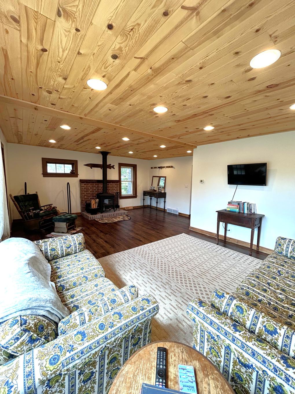 Living room with wood stove, mounted fish, and picture window