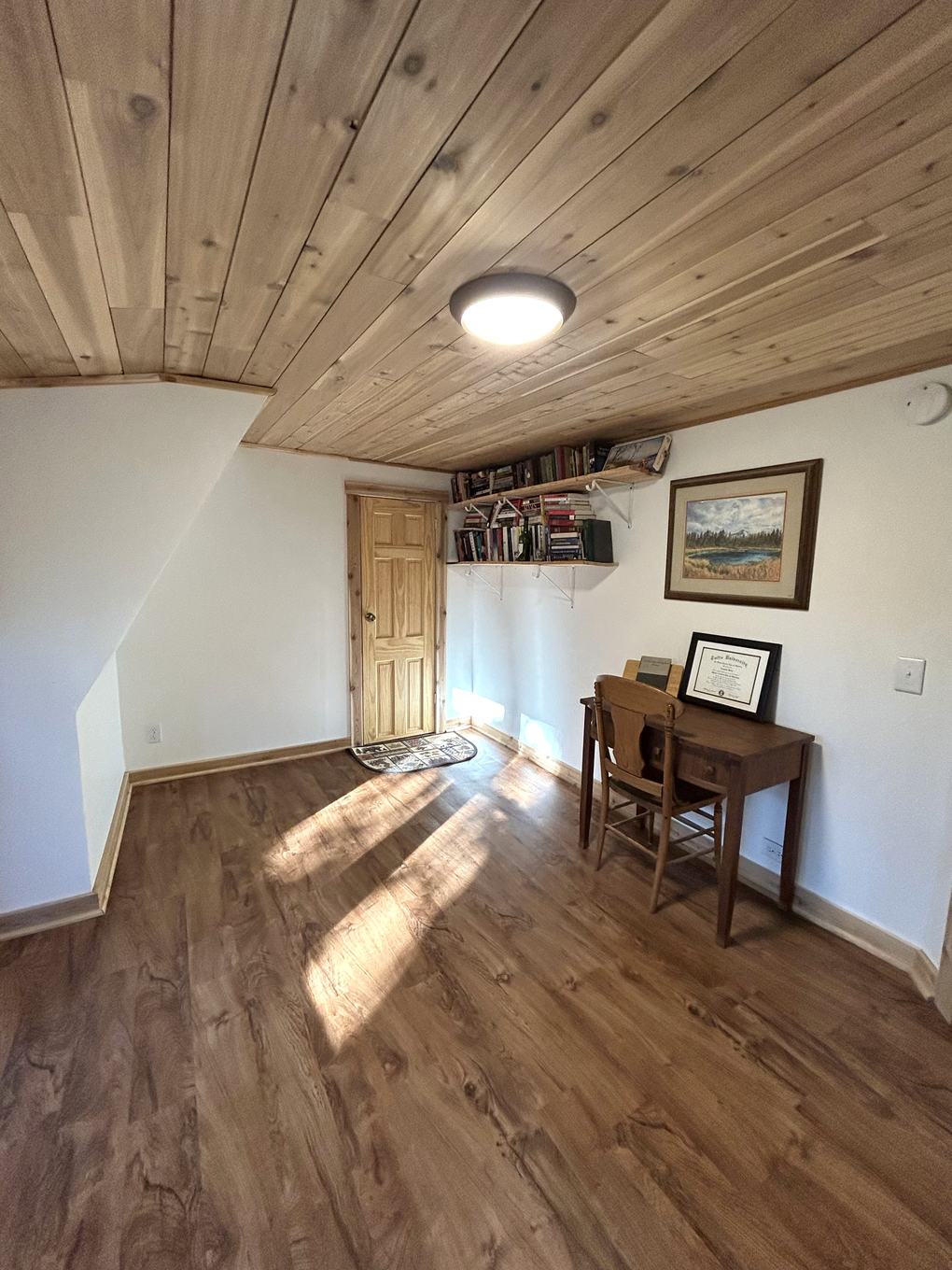 Home office nook with desk, bookshelf, and pine ceiling