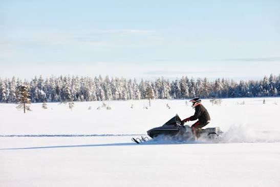 A snowmobiler crossing open snowy terrain near Lake Vermilion